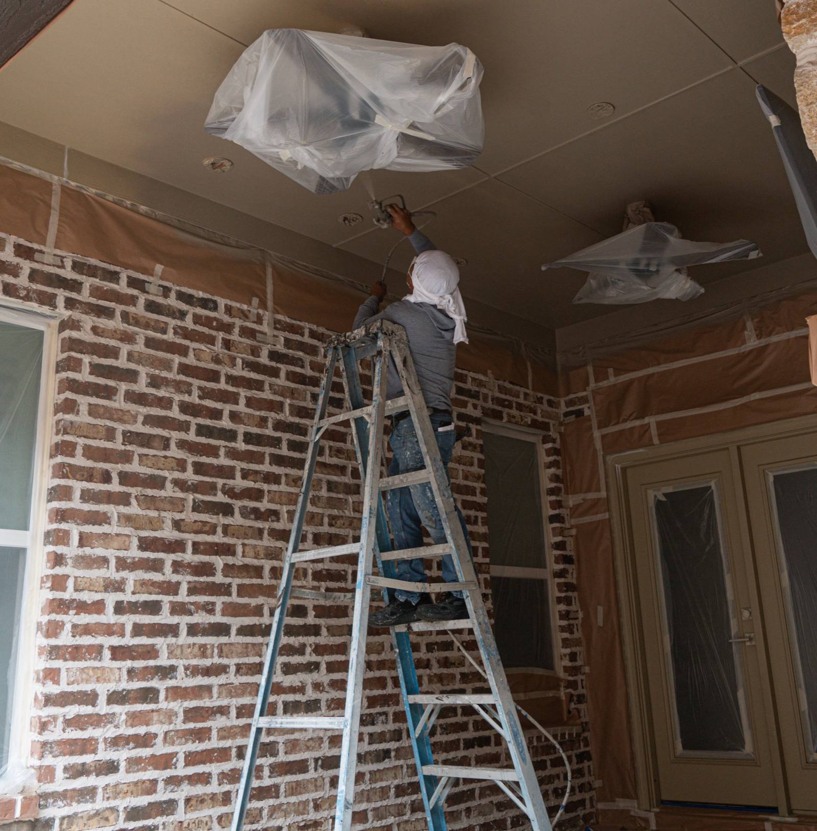 Optimized Painting Co. professional spraying a ceiling with careful masking